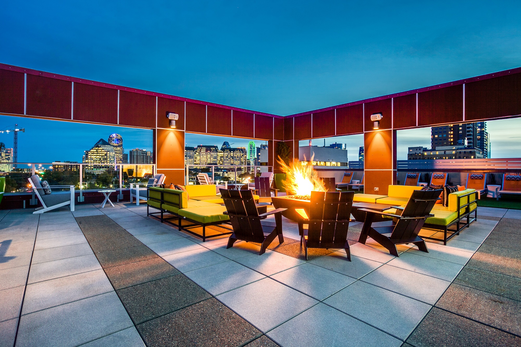 Evening shot of fire pit lounge with lighting, sectional seating and chairs/tables