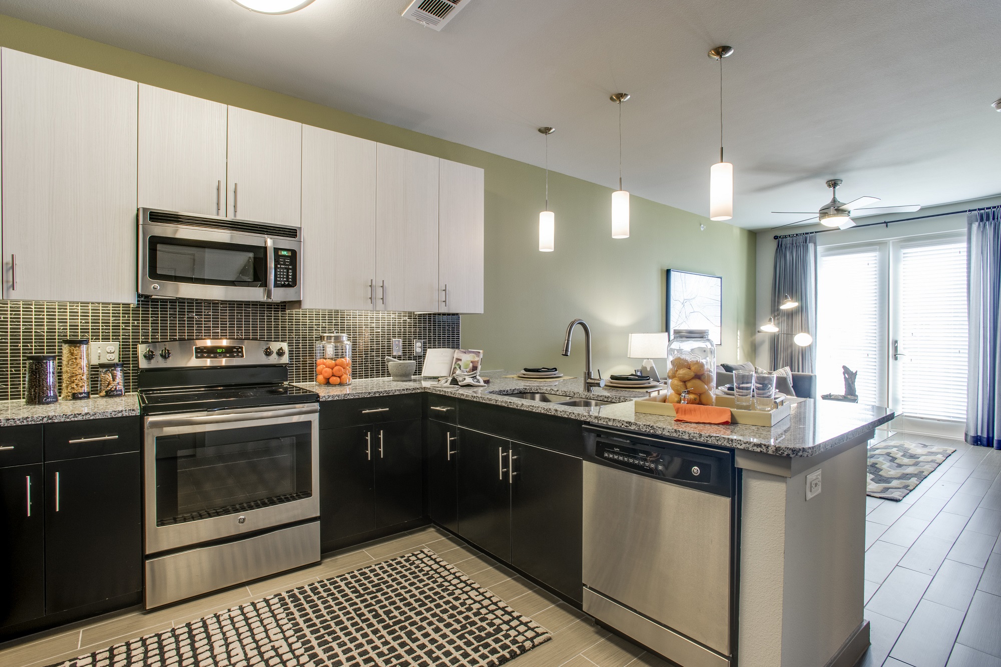 Kitchen with two tone cabinets, stainless steel appliances, granite counters and bar seating that is open to the living room