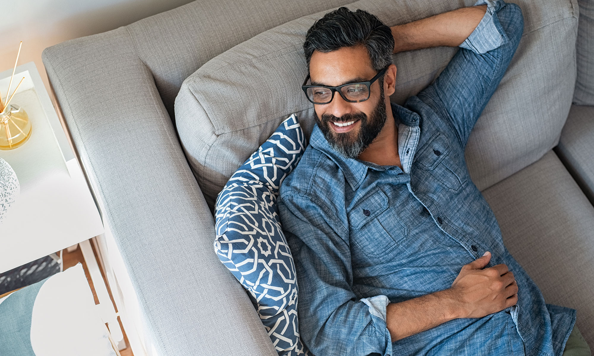 Man lounging on his couch at home smiling