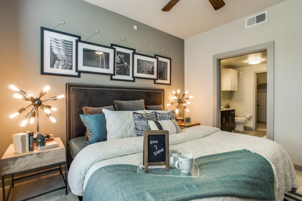 Bedroom with ceiling fan, accent wall, plush carpet and modern furniture that has a private bathroom